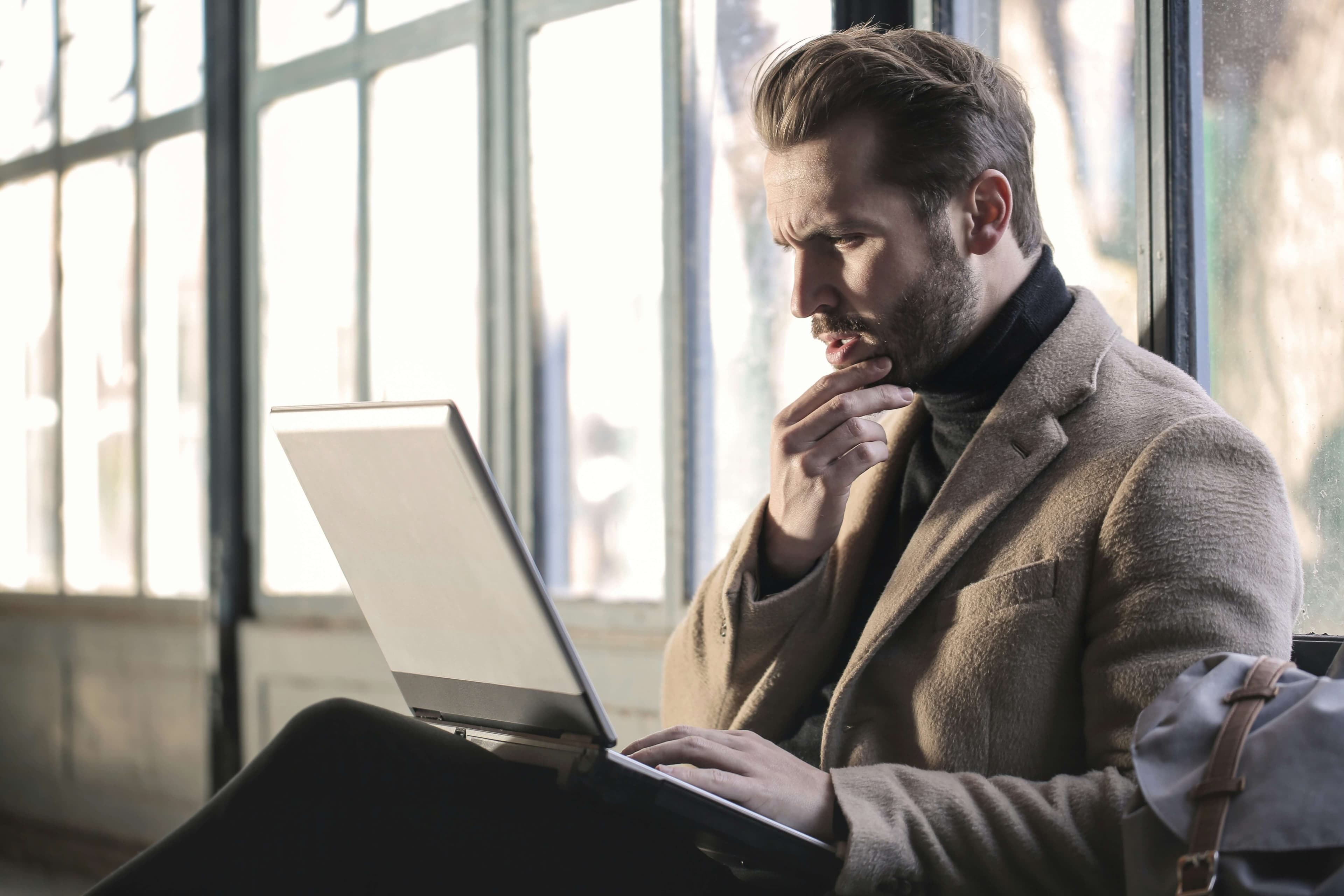 Man thinking and making financial decisions while looking at laptop computer